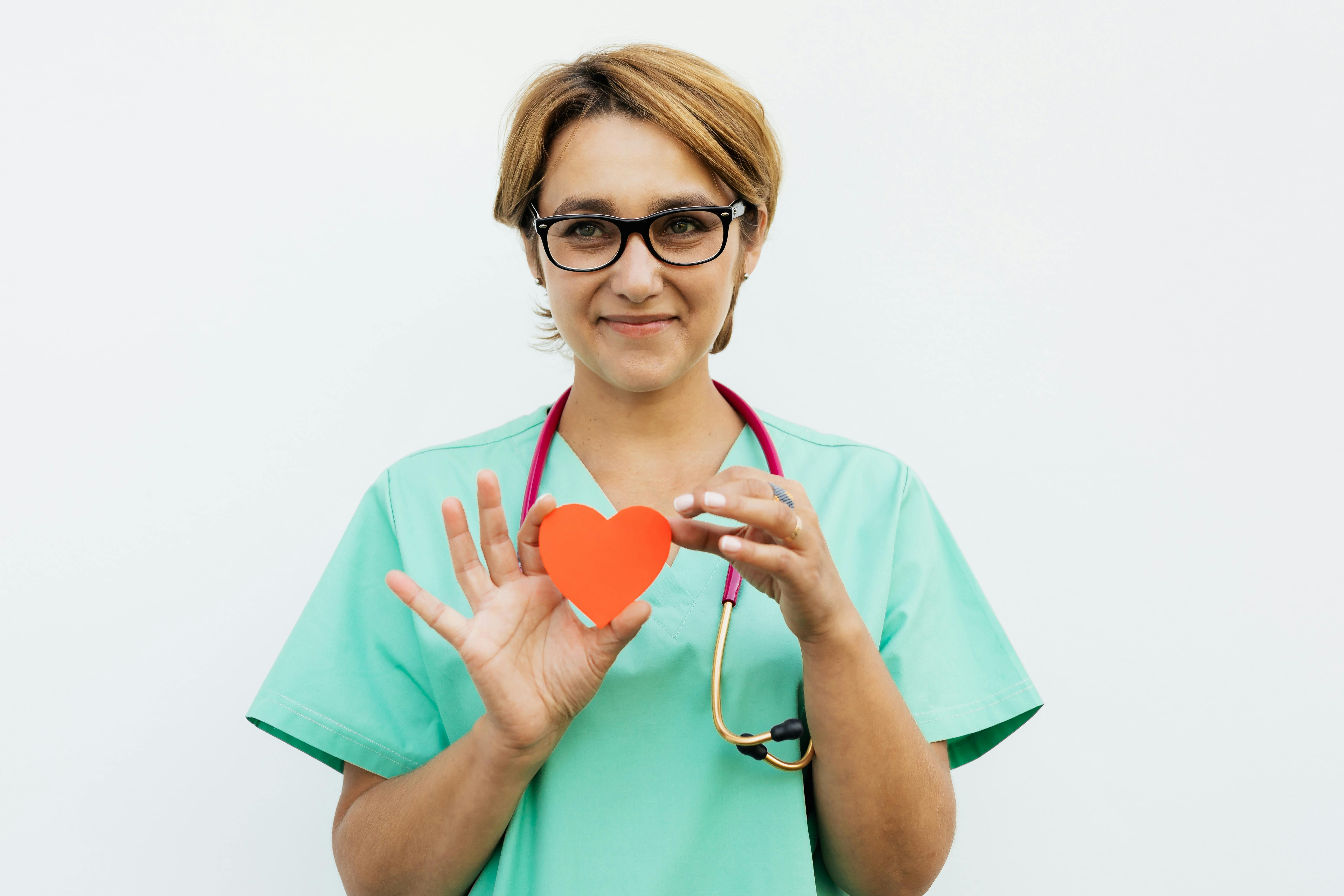 Nurse in scrubs holding a paper heart